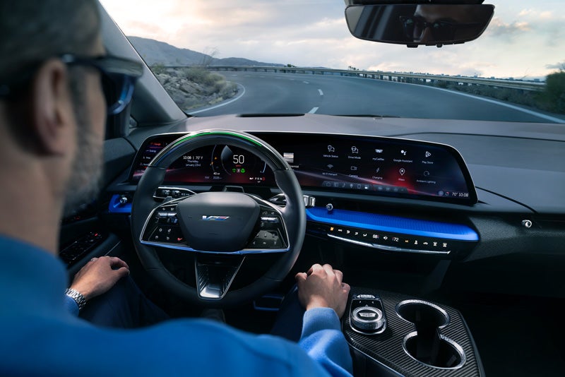 Front View of the 2026 OPTIQ-V Driving Through the Dusk Utilizing its Headlights | Key Cadillac in Edina MN