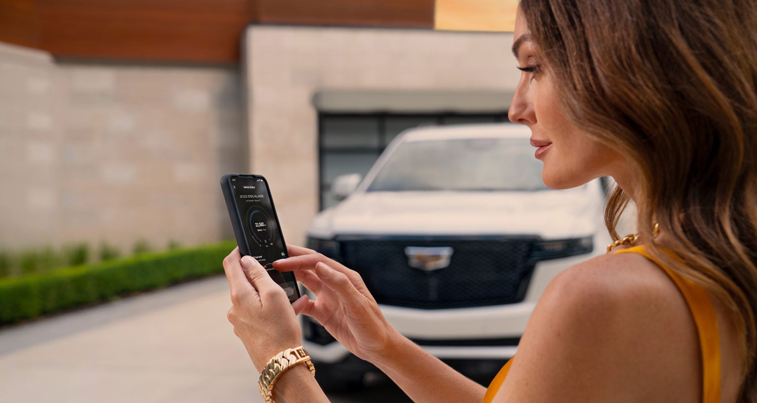 lady checking her mobile with a Cadillac vehicle background | Key Cadillac in Edina MN